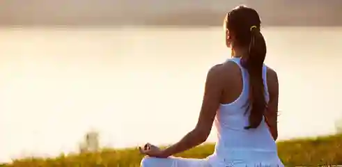 Femme qui médite au bord d'un lac